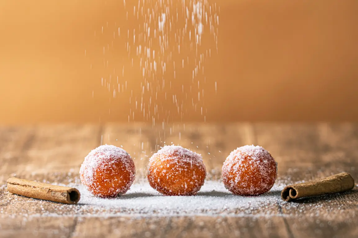 Commercial food photography - Motion shot of powdered sugar dusting over fluffy Greek donuts and cinnamon